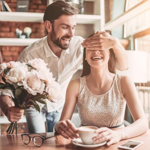 Man surprising woman with flowers,